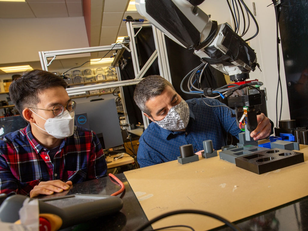 Alberto Rodriguez is a roboticist specializing in tactile sensing. Here, he and PhD student Sangwoon Kim (left) work with a robot arm tasked with blindly inserting an object into a hole. Credits:Photo: Tony Pulsone