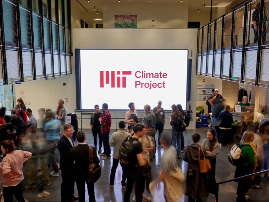 Many people mingling in open atrium in front of sign reading MIT Climate Project