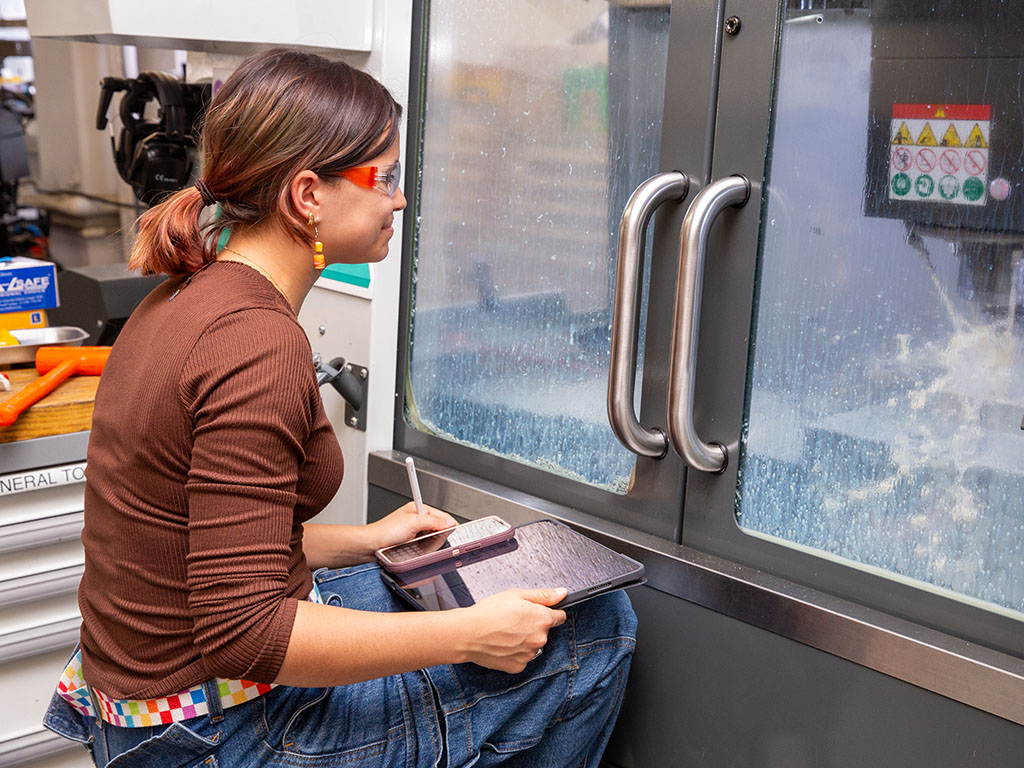 Paula Romero '27 looks patiently waits for the CNC Machine to complete its 3-Hour cutting run.
