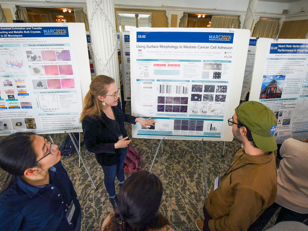 At a poster session, Caroline McCue explains her research to a handful of listeners.