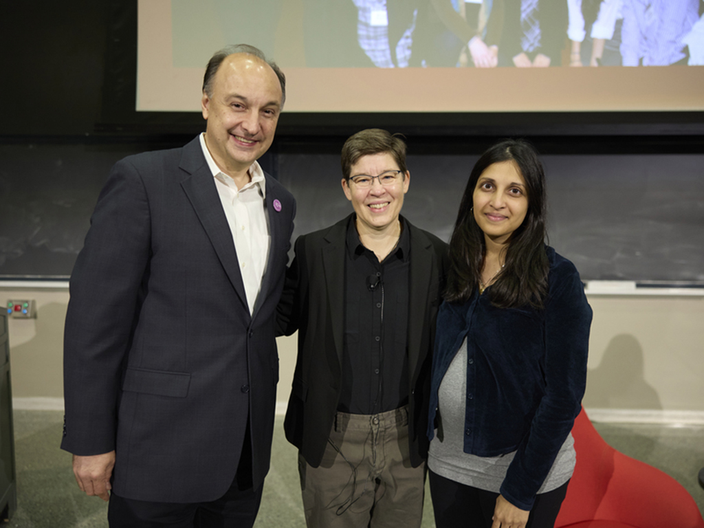 Three people stand on a stage