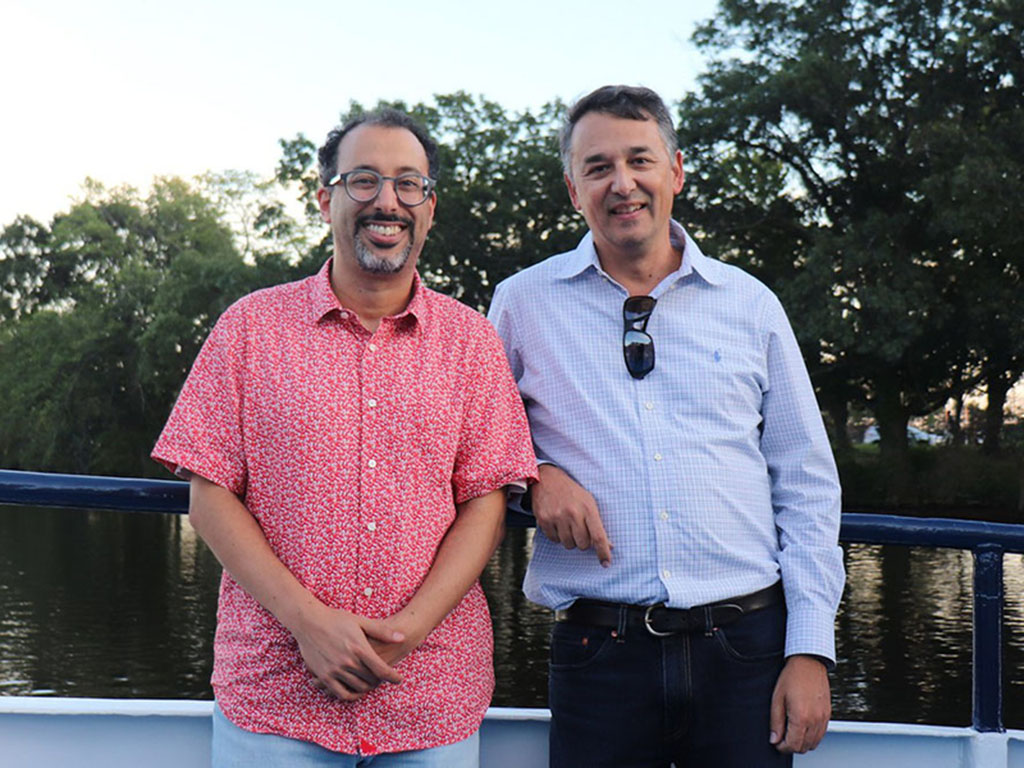 Youssef Marzouk and Nicolas Hadjiconstantinou pose with a body of water and trees in the background.