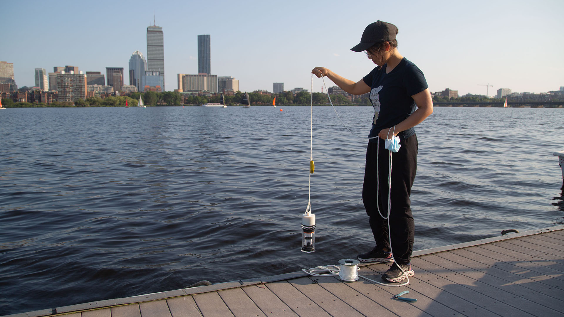 Person standing on a dock holding a device above the water.