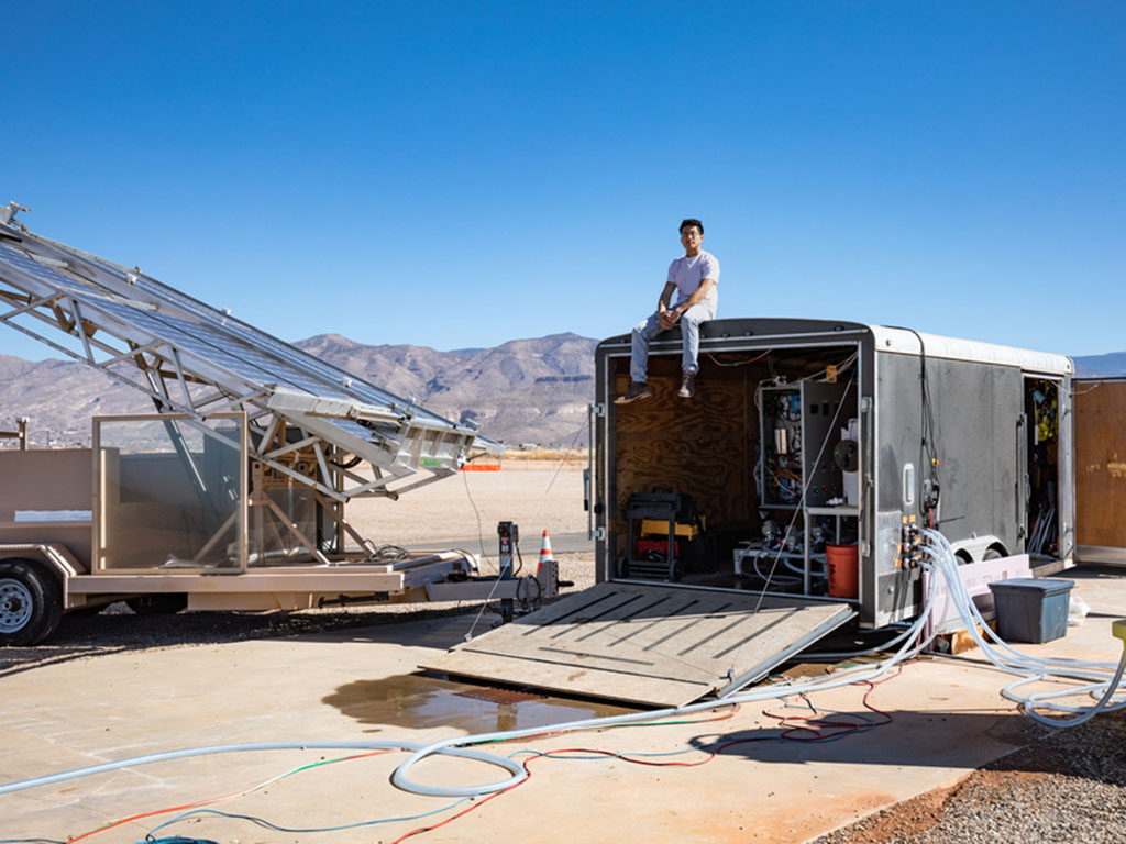 In rural New Mexico, a solar panel truck is next to a trailer with lots of hoses connected to it going many directions.