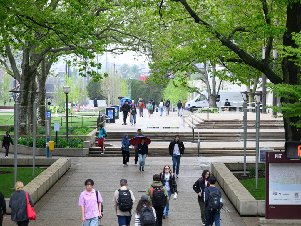 A photo of the MIT Campus. Groups of people walk outside near the student center.