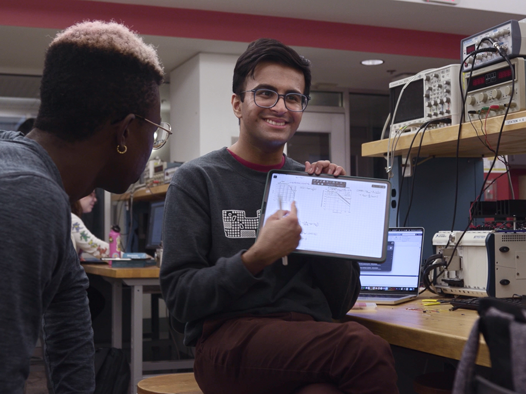 A smiling student holding his work. 