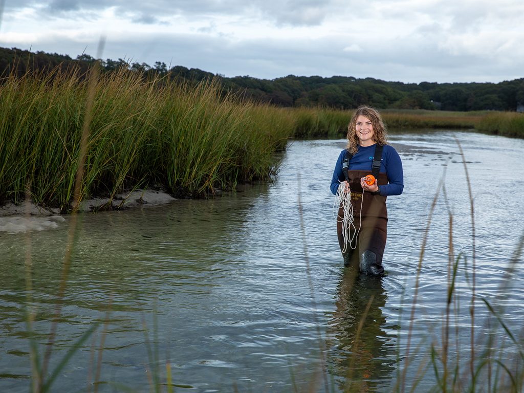 MIT graduate student Faith Brooks stands in a pond. She's conducting research on harmful algae blooms.