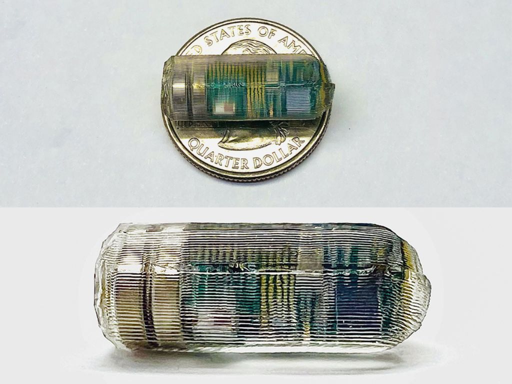 Collage: img 1 A tiny transparent pill with textured surface is on a table. You can barely see green computer chip inside. Img 2 The tiny pill sits on a quarter and is about the same length as the quarter’s diameter.