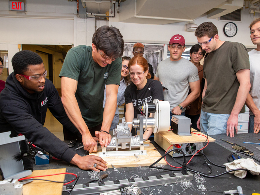 Students gather around a lathe they built in a class at MIT