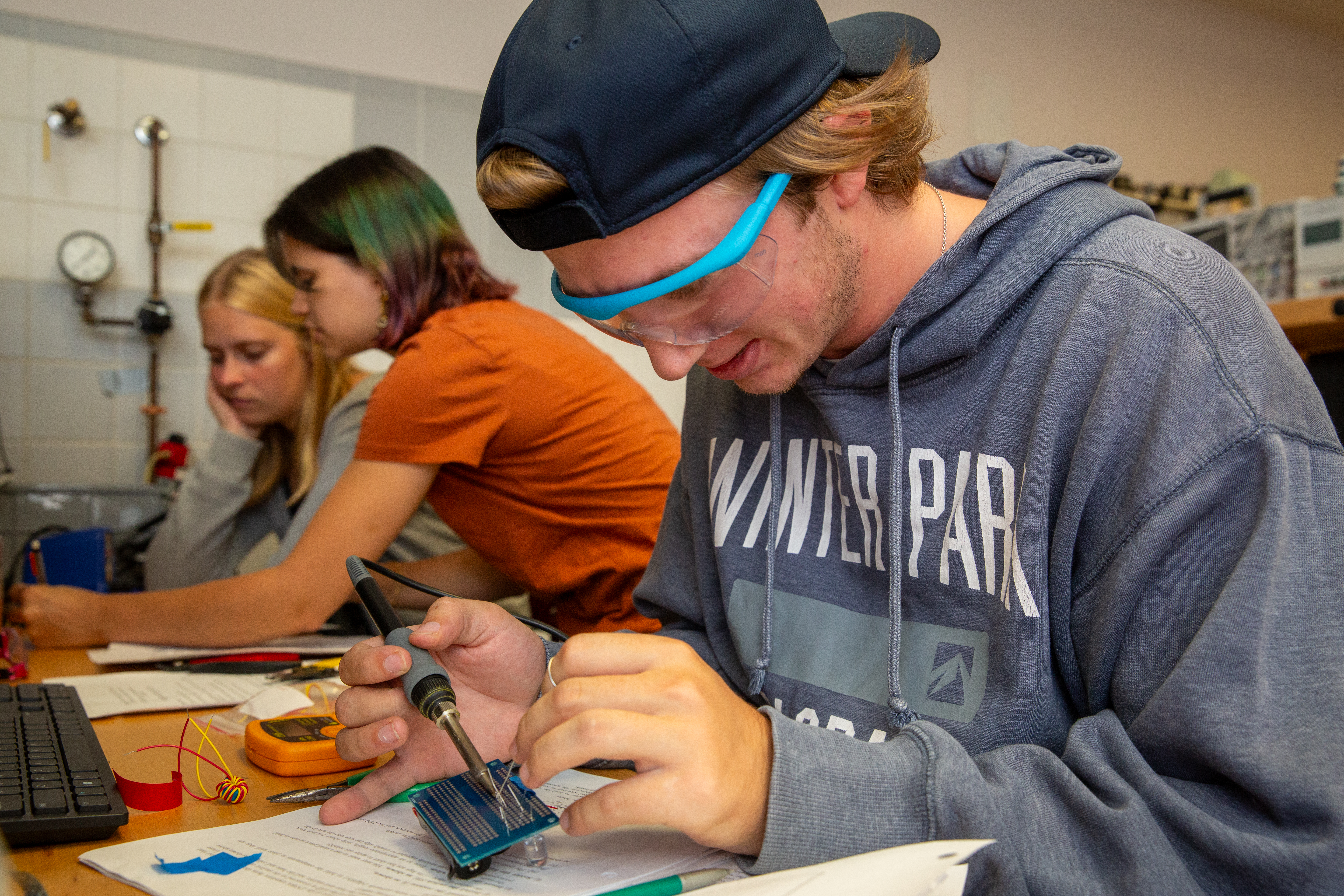 Carter Tucker works on solders a wire as part of a 2.678 Lab assignment